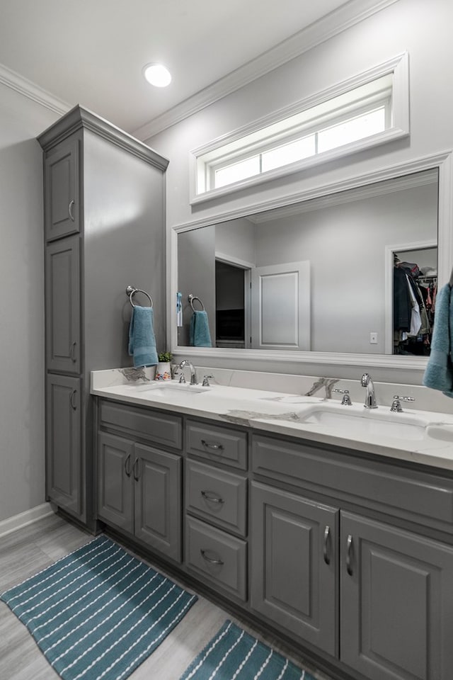 full bath with a sink, crown molding, double vanity, and wood finished floors