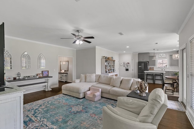 living room featuring dark wood-type flooring, baseboards, visible vents, ceiling fan, and ornamental molding