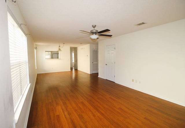 empty room with a textured ceiling, ceiling fan, and dark wood-type flooring