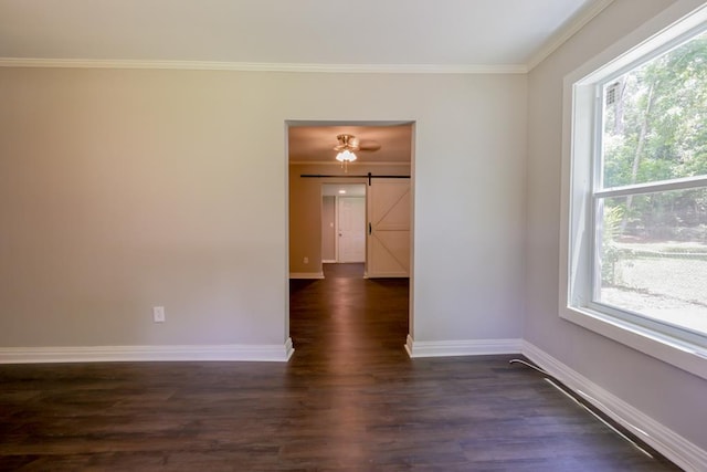 spare room featuring plenty of natural light, a barn door, crown molding, and dark hardwood / wood-style floors