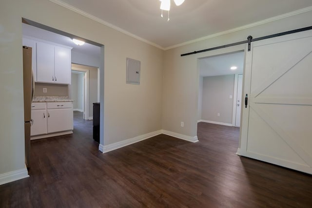 unfurnished room featuring a barn door, crown molding, dark wood-type flooring, and electric panel