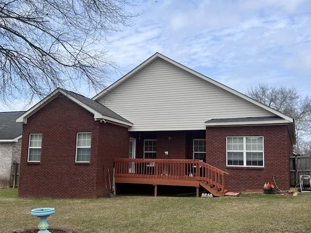 rear view of house with brick siding, a wooden deck, and a yard