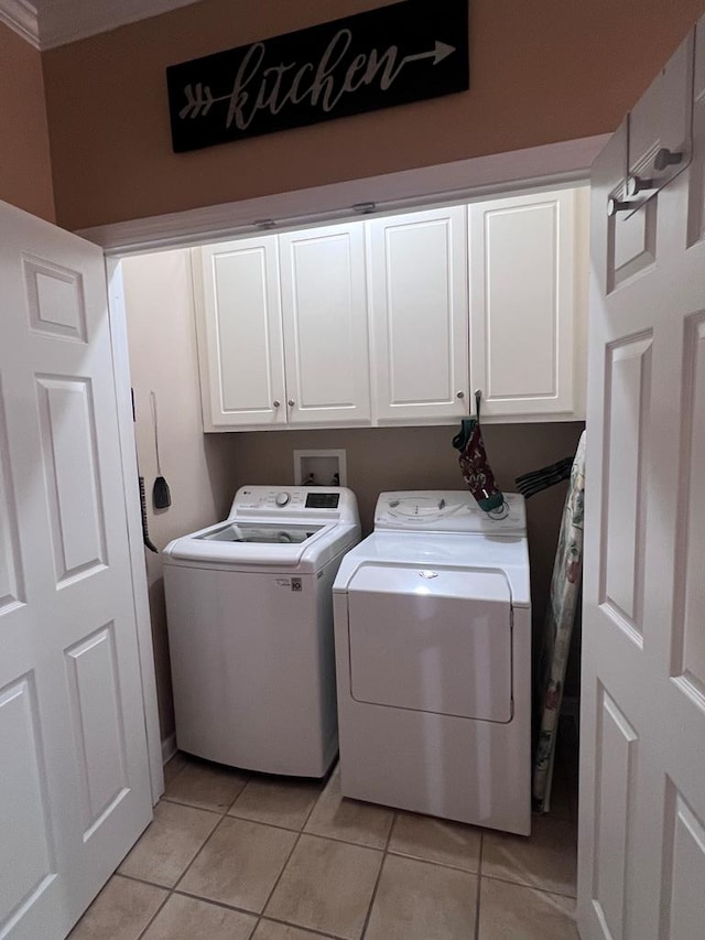 clothes washing area featuring light tile patterned flooring, cabinet space, and washer and dryer