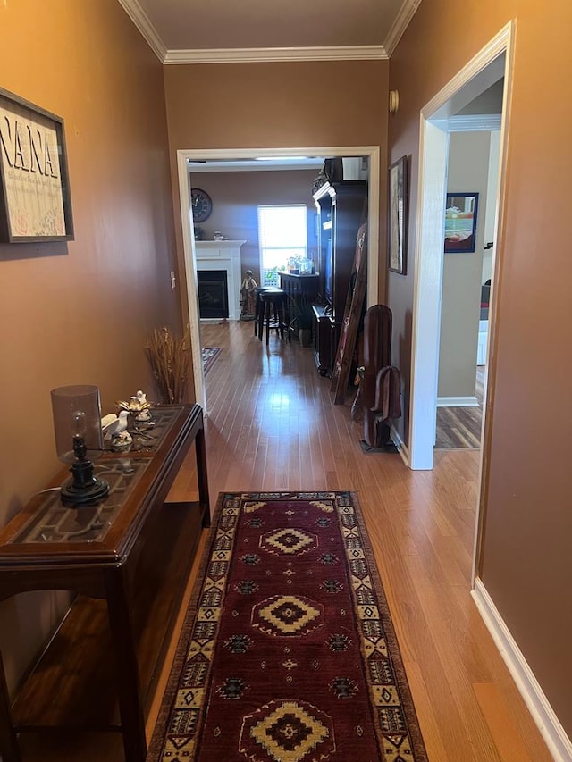 corridor featuring crown molding, baseboards, and wood finished floors