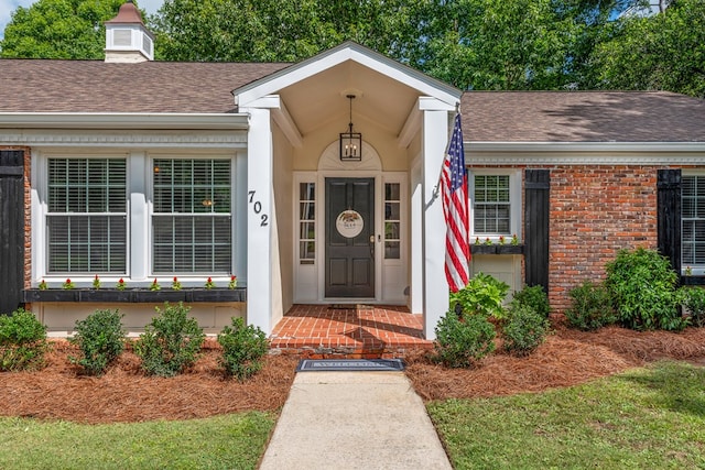 702 W Lee St, Enterprise, AL 36330 - view of exterior entry featuring a shingled roof, brick siding, and a chimney