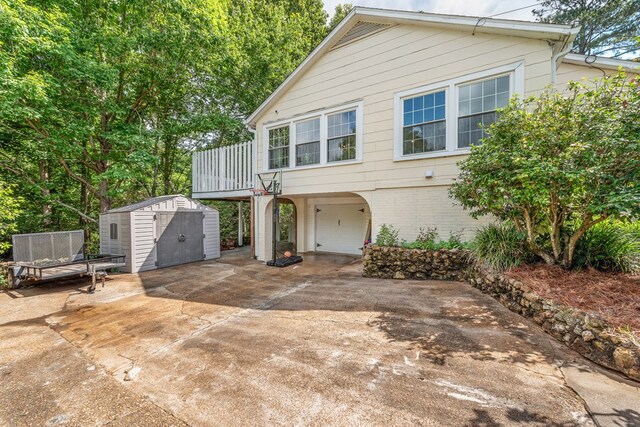 702 W Lee St, Enterprise, AL 36330 - view of front of home featuring a storage shed, an attached garage, brick siding, driveway, and a wooden deck