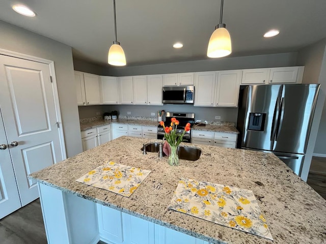 kitchen with hanging light fixtures, light stone countertops, white cabinets, and appliances with stainless steel finishes