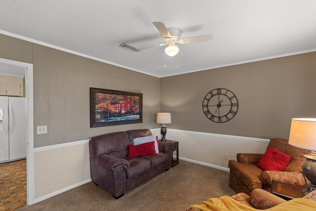 living room featuring a textured ceiling, ceiling fan, crown molding, and carpet