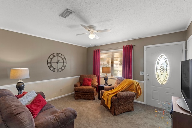 carpeted living room featuring ceiling fan, ornamental molding, and a textured ceiling