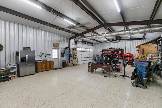 garage featuring stainless steel refrigerator with ice dispenser, visible vents, and a workshop area