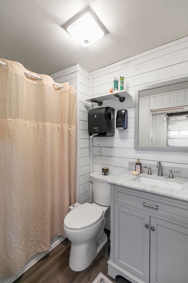 full bath featuring vanity, wood walls, wood finished floors, toilet, and a shower with curtain