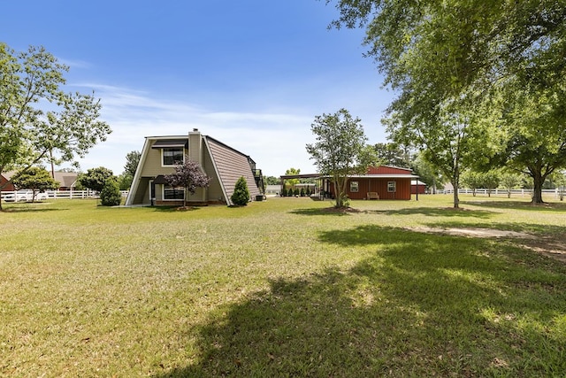 view of yard featuring a pole building, fence, and an outbuilding