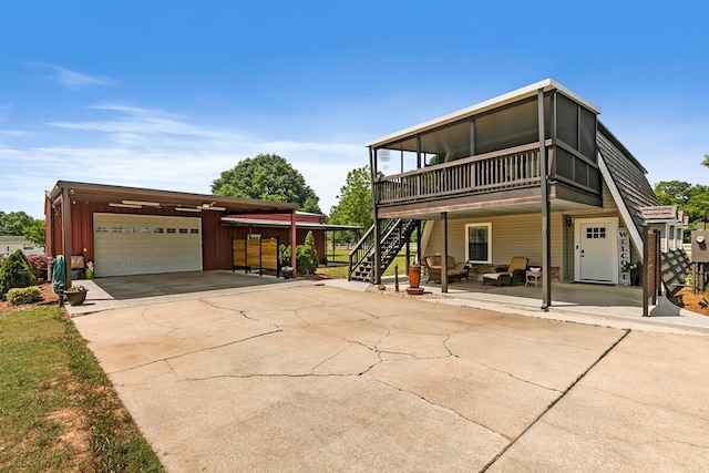 back of property with stairway, a deck, an attached garage, and driveway