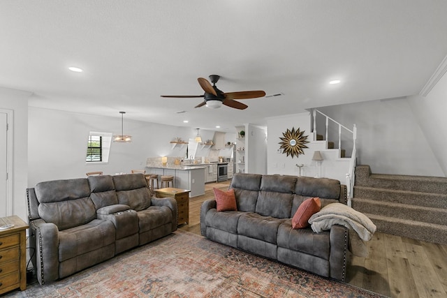 living room featuring a ceiling fan, visible vents, stairs, wood finished floors, and recessed lighting
