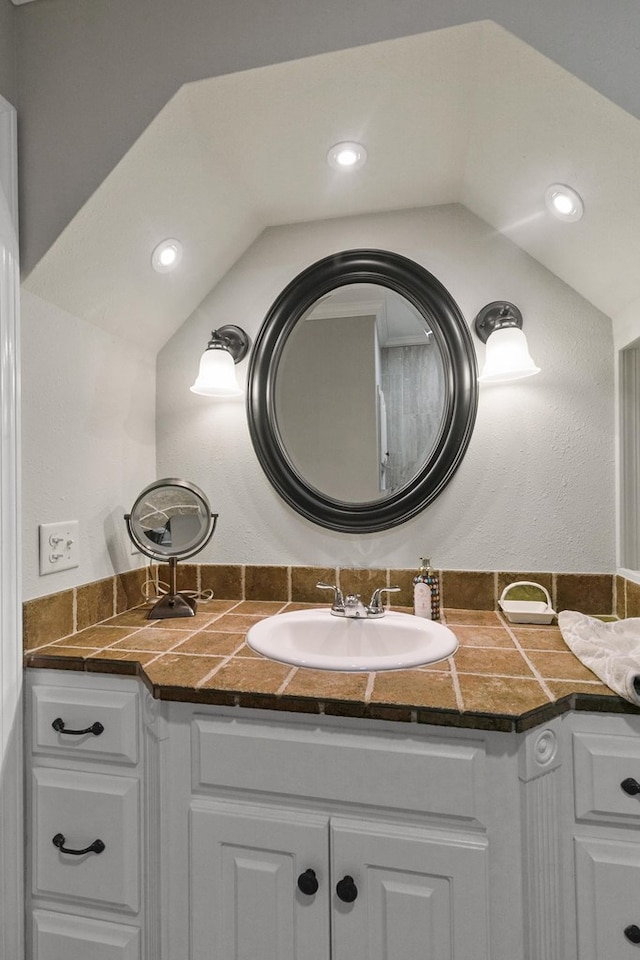 bathroom featuring vanity, recessed lighting, and lofted ceiling
