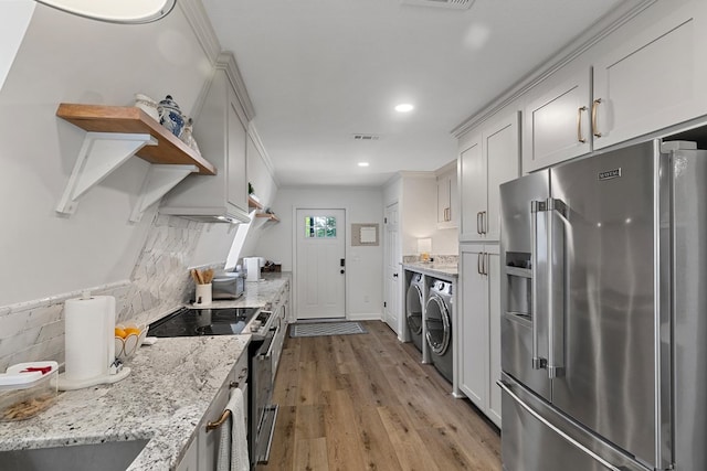 kitchen featuring washing machine and clothes dryer, tasteful backsplash, open shelves, light wood-type flooring, and stainless steel appliances