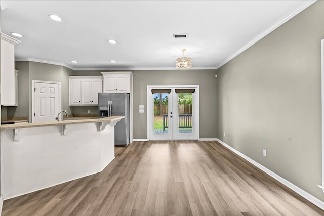 133 Brockton Ct, Dothan, AL 36305 - kitchen with stainless steel fridge with ice dispenser, a breakfast bar, wood finished floors, french doors, and white cabinetry
