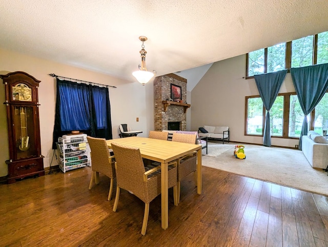 dining space featuring dark hardwood / wood-style floors, a textured ceiling, and a brick fireplace