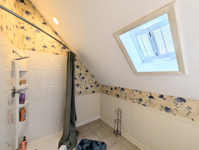 3602 Pebble Creek Ln, Dothan, AL 36303 - bathroom featuring lofted ceiling, a wainscoted wall, wallpapered walls, tiled shower, and a skylight