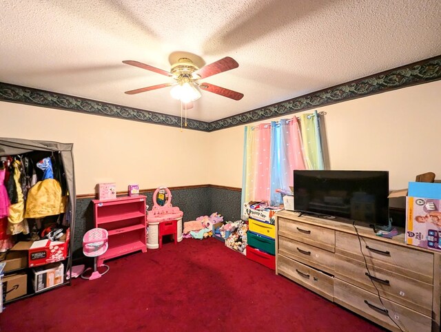 recreation room with carpet flooring, a textured ceiling, and ceiling fan