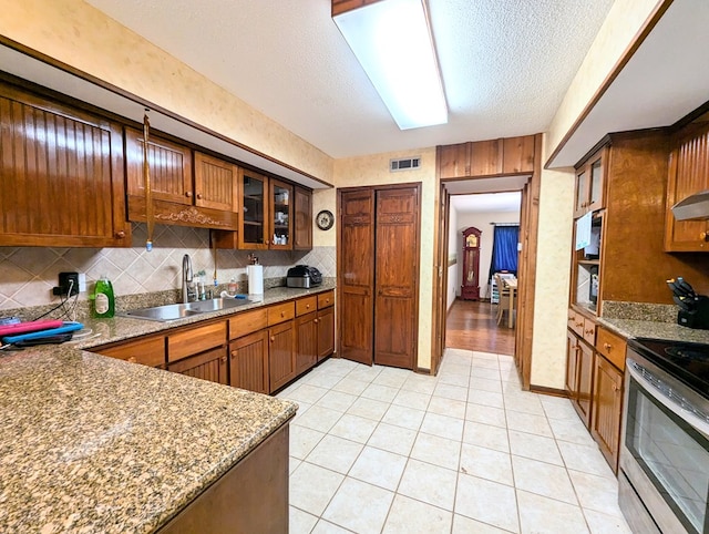 kitchen featuring sink, tasteful backsplash, a textured ceiling, stainless steel range with electric stovetop, and light tile patterned flooring