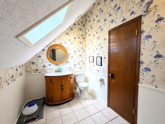 3602 Pebble Creek Ln, Dothan, AL 36303 - bathroom featuring wallpapered walls, a skylight, wainscoting, tile patterned floors, and toilet