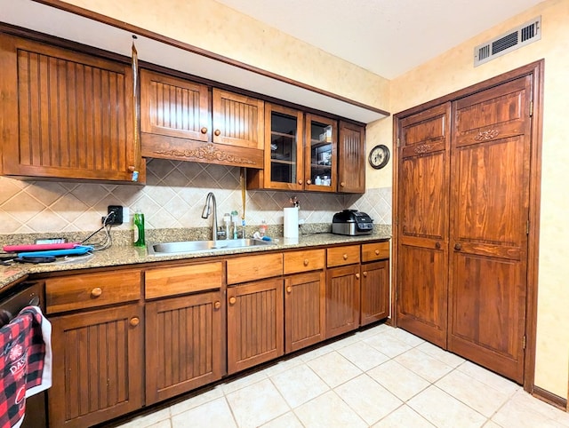 kitchen featuring light stone countertops, sink, tasteful backsplash, and light tile patterned flooring