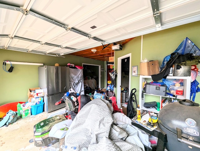 garage with stainless steel refrigerator and a garage door opener