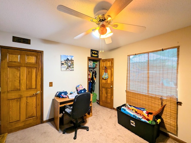 carpeted office space featuring ceiling fan and a textured ceiling