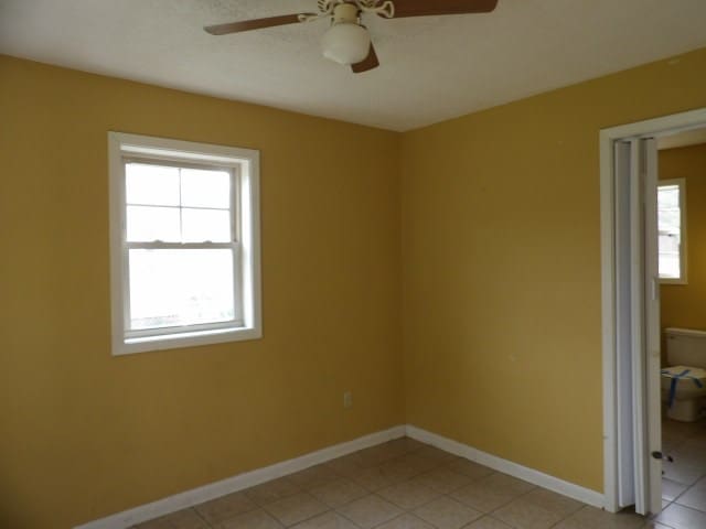 tiled empty room featuring ceiling fan