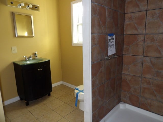 bathroom featuring tiled shower, tile patterned floors, vanity, and toilet