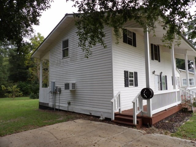 view of side of home with covered porch and a yard