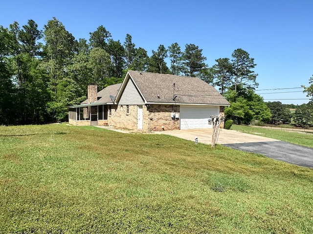 view of home's exterior featuring a chimney, driveway, a garage, a sunroom, and a lawn