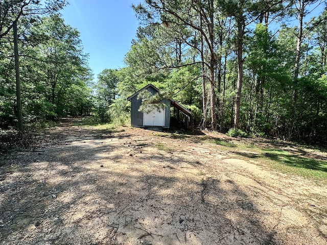 view of yard with a forest view, an outdoor structure, and a storage unit