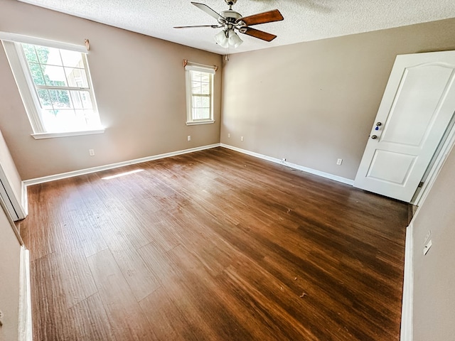 empty room with baseboards, a ceiling fan, wood finished floors, and a textured ceiling