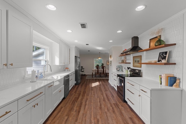 kitchen with crown molding, wall chimney range hood, white cabinets, and stainless steel appliances