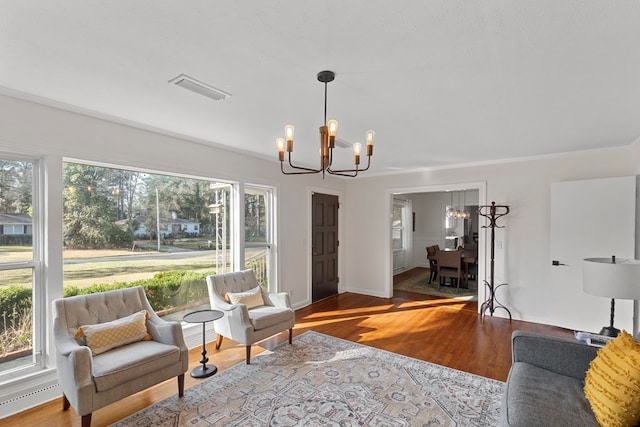 living room with ornamental molding, hardwood / wood-style floors, and an inviting chandelier