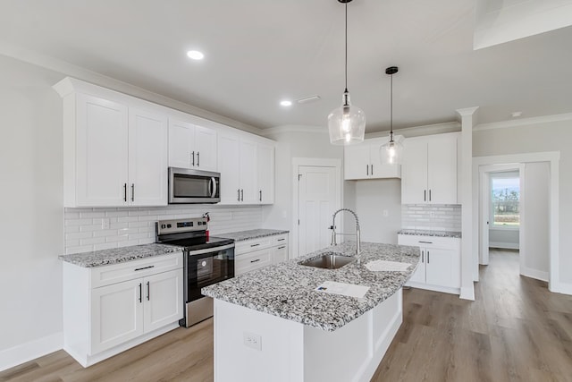 kitchen with white cabinetry, stainless steel appliances, and an island with sink