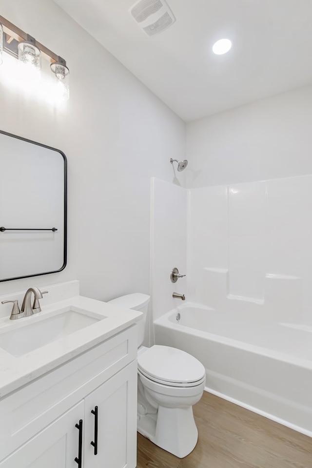 full bathroom with vanity, hardwood / wood-style floors, washtub / shower combination, and toilet