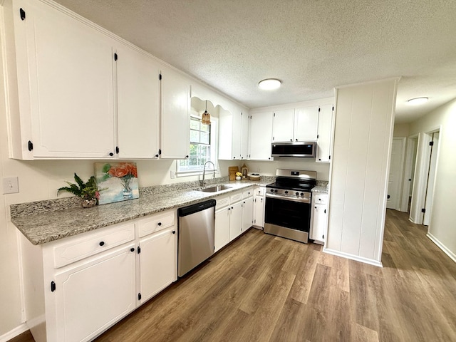 143 Durby Ln, Dothan, AL 36305 - kitchen featuring stainless steel appliances, wood finished floors, a textured ceiling, white cabinetry, and light stone countertops