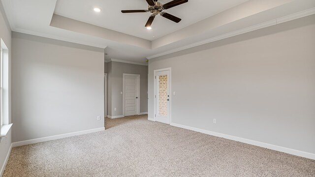 spare room with ceiling fan, ornamental molding, a tray ceiling, and dark carpet