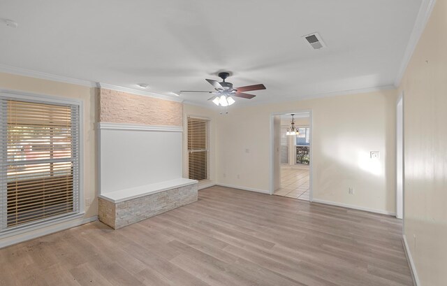 unfurnished living room with ornamental molding, ceiling fan with notable chandelier, light wood-type flooring, and visible vents