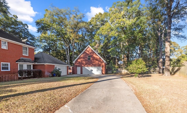 view of front facade featuring fence, a detached garage, an outdoor structure, and concrete driveway
