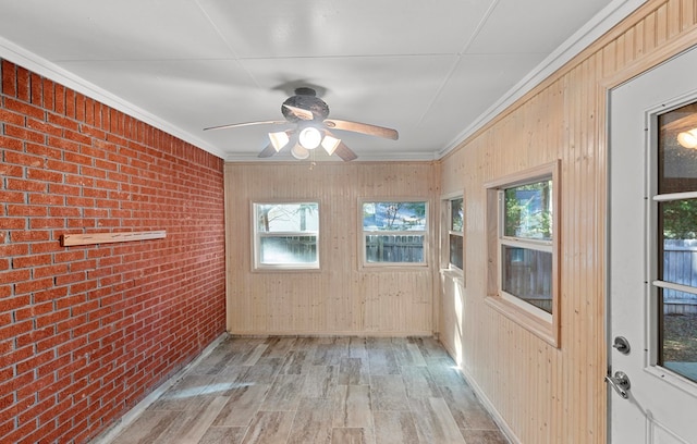 unfurnished sunroom featuring crown molding, brick wall, and wood finished floors