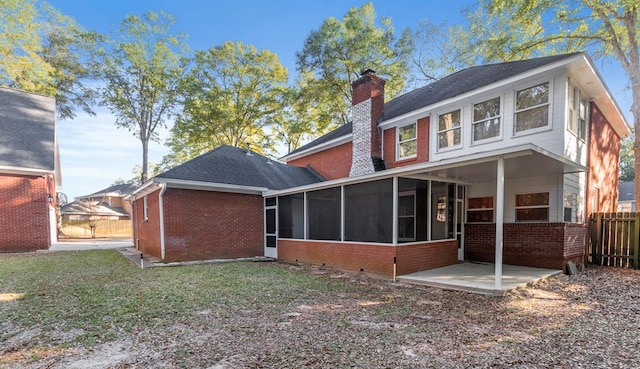 rear view of house with brick siding, fence, a chimney, and a sunroom