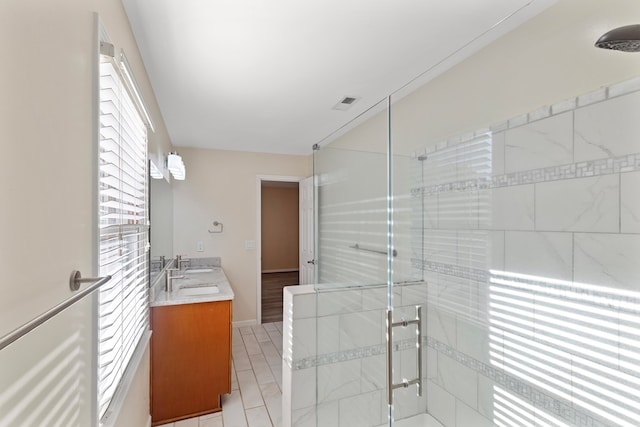 full bath with double vanity, visible vents, a shower stall, and a sink