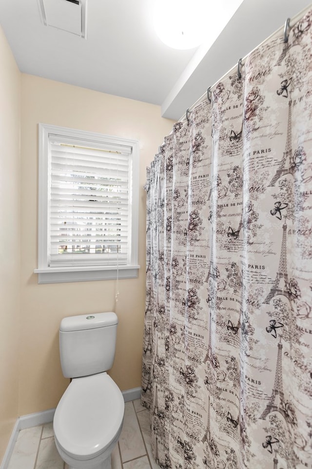 bathroom with toilet, baseboards, and curtained shower
