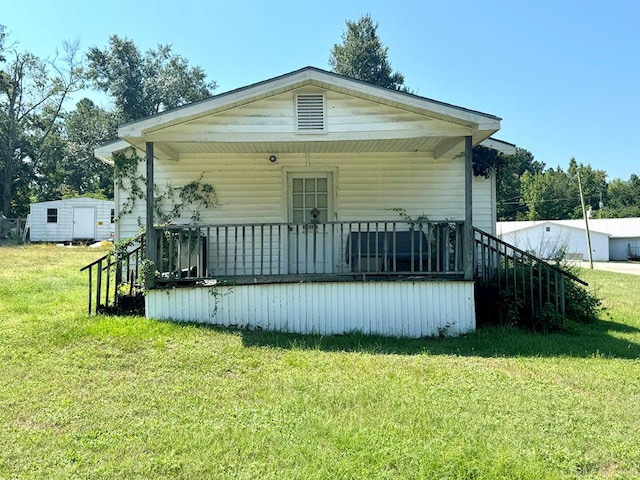 back of property with a lawn, a porch, and a storage shed