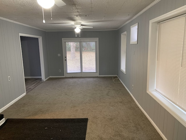 empty room with visible vents, ornamental molding, a ceiling fan, carpet flooring, and baseboards