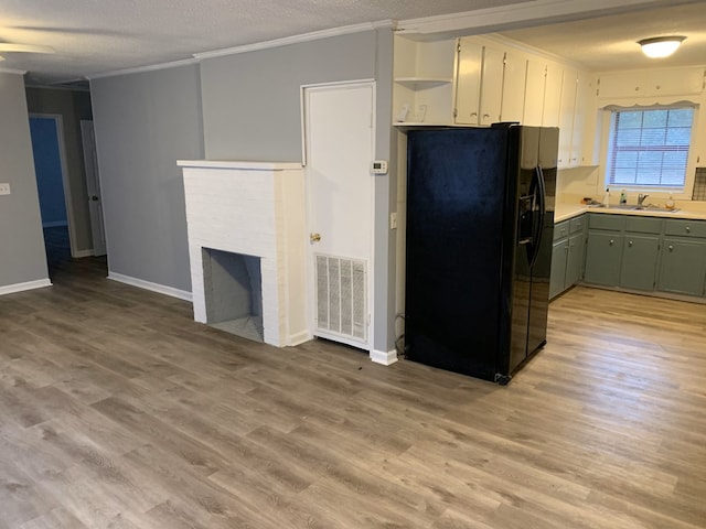 kitchen featuring a fireplace, a sink, visible vents, black refrigerator with ice dispenser, and crown molding